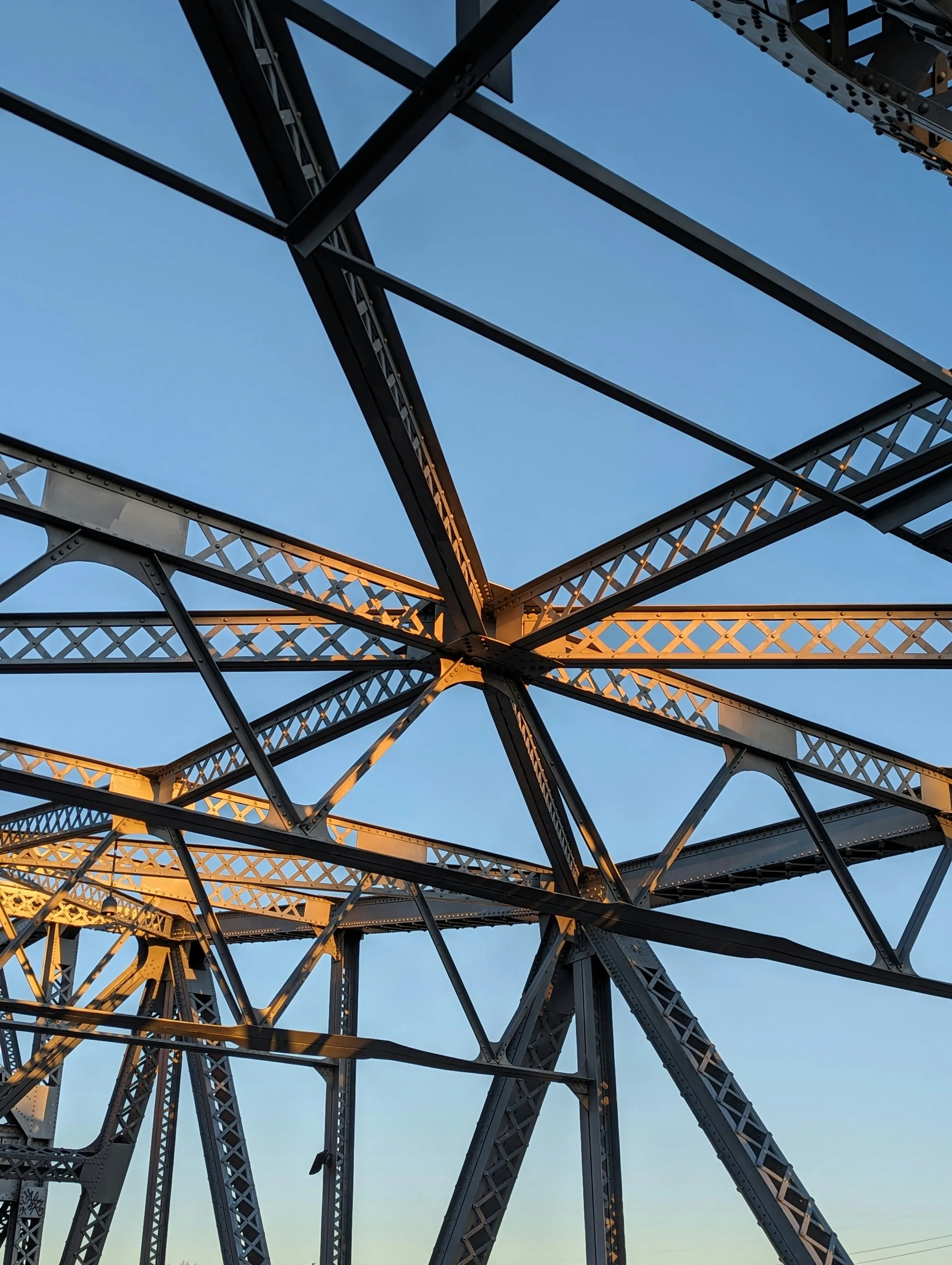 Stahlträger einer Brücke im Abendlicht vor blauem Himmel